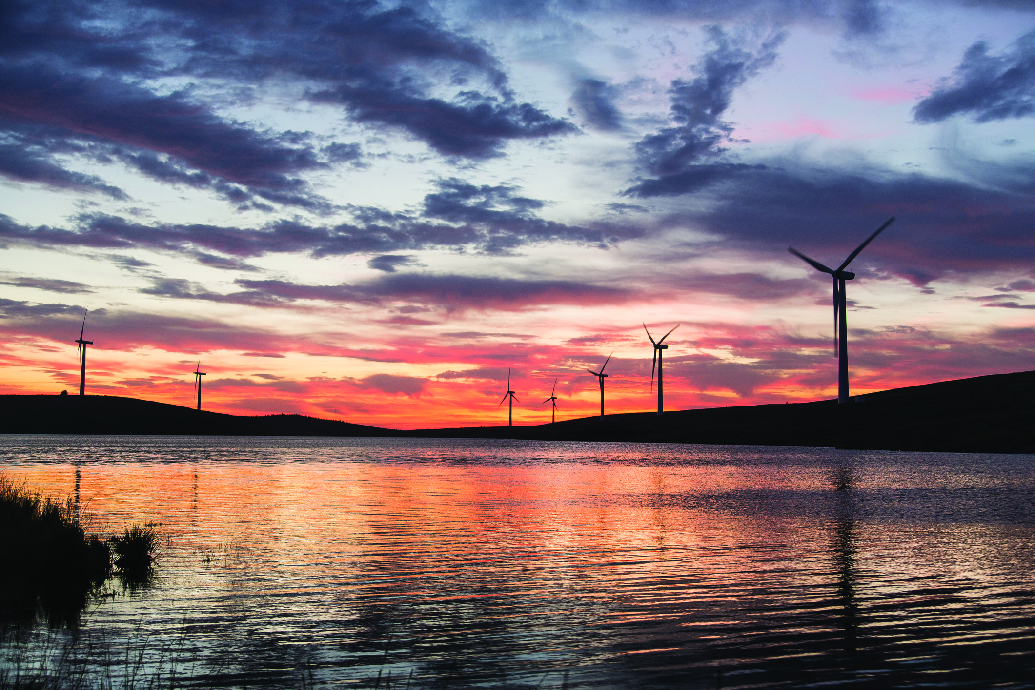 Wind turbines behind a lake at sunset