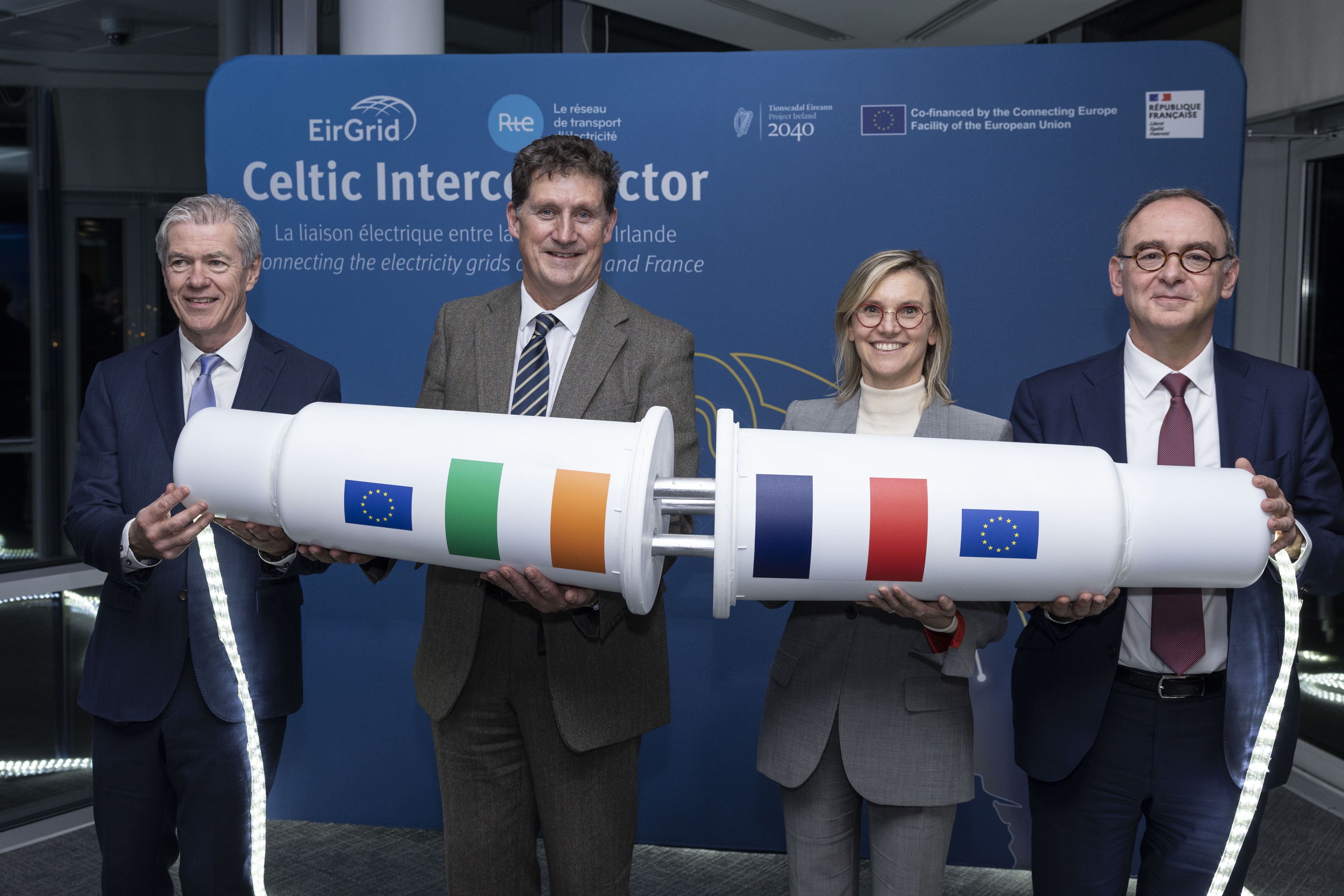 Senior executives and ministers hold a prop symbolising interconnection between Ireland and France